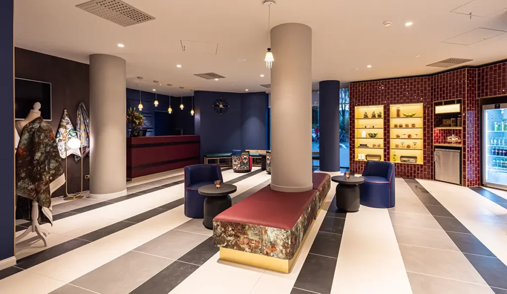 Die Lobby mit Sitzmöglichkeiten und Rezeption, Regalen und Kühlschrank im Hintergrund