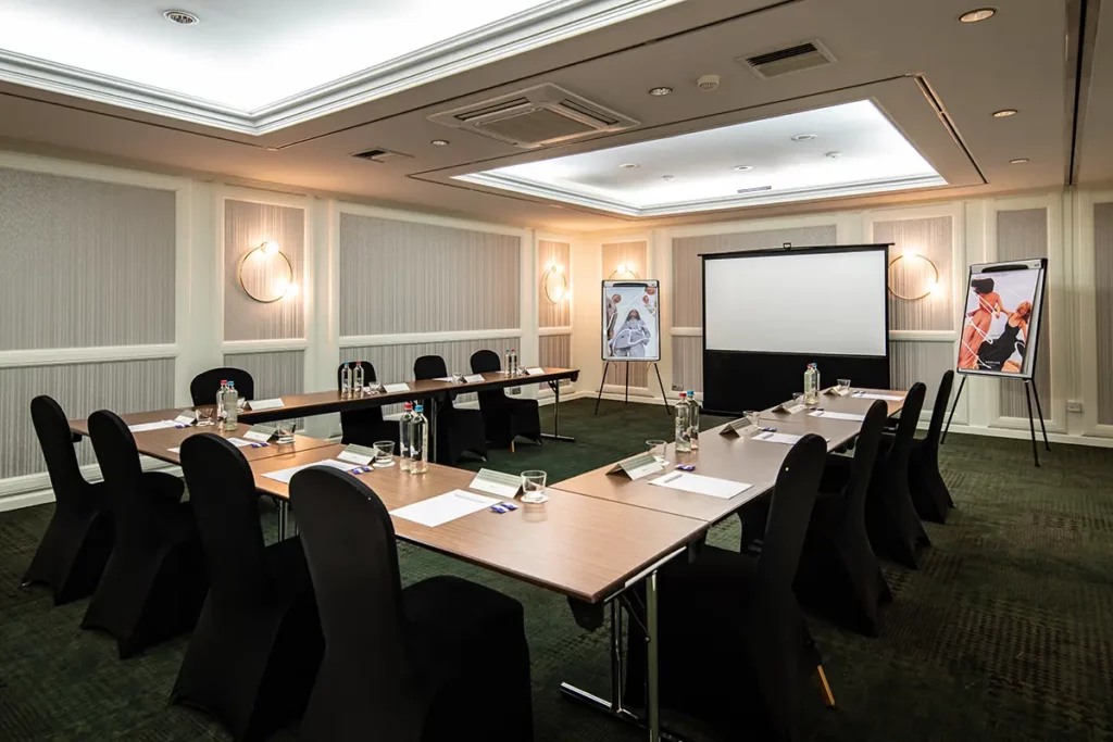 Der Basement Meetingraum mit Tischen und der U-Form und Stühlen rundherum.